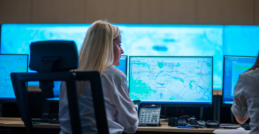 Agente policial em frente a uma tela de computador analisando um mapa. A imagem representa o uso de Google Cloud e Maps para análises de Segurança Pública.