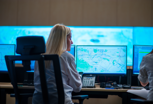 Agente policial em frente a uma tela de computador analisando um mapa. A imagem representa o uso de Google Cloud e Maps para análises de Segurança Pública.