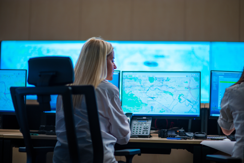 Agente policial em frente a uma tela de computador analisando um mapa. A imagem representa o uso de Google Cloud e Maps para análises de Segurança Pública.